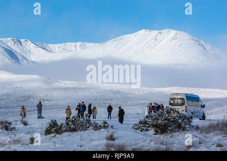 Visitatori, turisti, persone a godersi il paesaggio invernale su un minibus tour. Loch Tulla Viewpoint, A82 road avvicinando Rannoch Moor, Scozia. Foto Stock