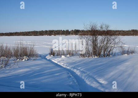 Il percorso che conduce attraverso la neve sul ghiaccio del fiume frosty giornata di sole. Foto Stock