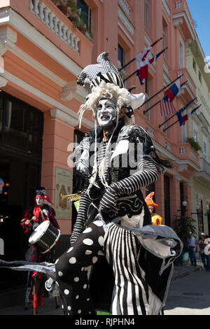 Un teatro di strada giocatore con una faccia dipinta e selvaggio circa costume intrattiene la folla per le strade di La Habana Vieja Cuba Foto Stock