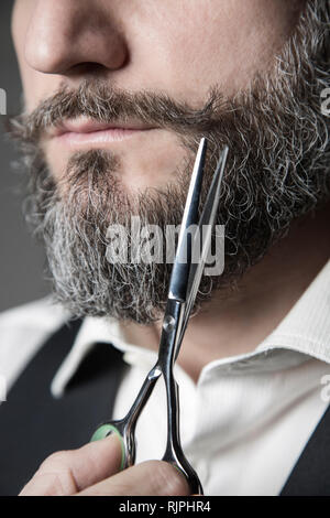 Close-up immagine raffigurante l atto di correggere baffi con forbici da barbiere Foto Stock