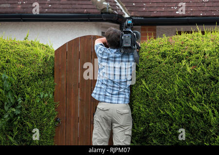 Una telecamera uomo film oltre il cancello del giardino del boss mafioso Domenico Rancadore, voleva su un mandato di arresto europeo. Londra. Il 9 agosto 2013. Foto Stock