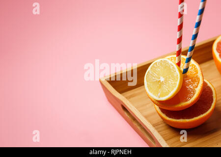 Tagliato a metà succosa agrumi su uno sfondo rosa su un vassoio accanto a un bicchiere di succo di frutta Foto Stock