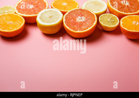 Splendidamente fette di arance, limoni, mandarini e gli altri agrumi su un gradevole sfondo rosa Foto Stock