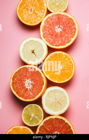 Splendidamente fette di arance, limoni, mandarini e gli altri agrumi su un gradevole sfondo rosa Foto Stock