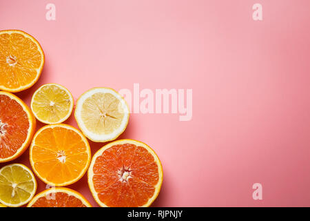 Splendidamente fette di arance, limoni, mandarini e gli altri agrumi su un gradevole sfondo rosa Foto Stock