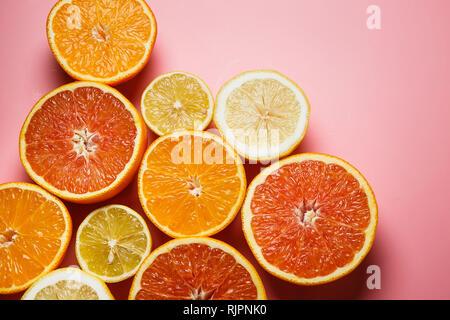 Splendidamente fette di arance, limoni, mandarini e gli altri agrumi su un gradevole sfondo rosa Foto Stock