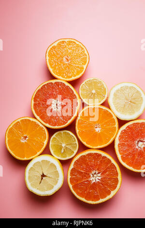 Splendidamente fette di arance, limoni, mandarini e gli altri agrumi su un gradevole sfondo rosa Foto Stock