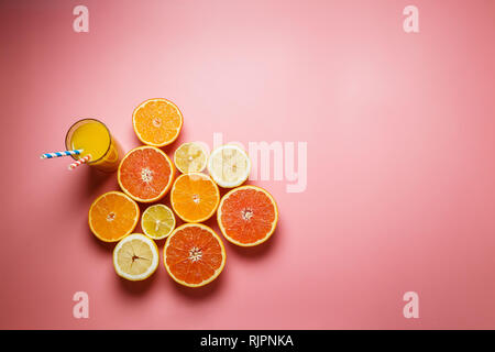 Splendidamente fette di arance, limoni, mandarini e gli altri agrumi su un gradevole sfondo rosa Foto Stock