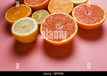 Splendidamente fette di arance, limoni, mandarini e gli altri agrumi su un gradevole sfondo rosa Foto Stock