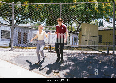 Giovane femmina dando ad un amico una mano nel parco, Los Angeles, California, Stati Uniti d'America Foto Stock