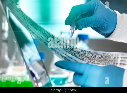 Research Scientist tenendo un campione in una fiala con risultati di DNA su gel autoradiogramma in laboratorio, stretta di mano Foto Stock