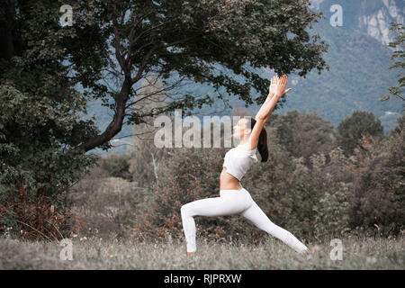 Donna pratica lo yoga, guerriero pongono nel paesaggio rurale Foto Stock