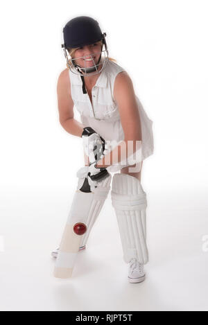 Donna cricketer in un abito bianco con un casco di protezione, parastinchi, un bat e la sfera. Foto Stock