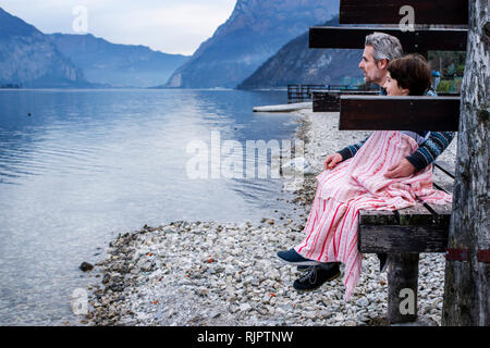 Ragazzo e padre avvolto in un lenzuolo sul molo di lakeside, vista laterale, Lago di Como, Onno, Lombardia, Italia Foto Stock