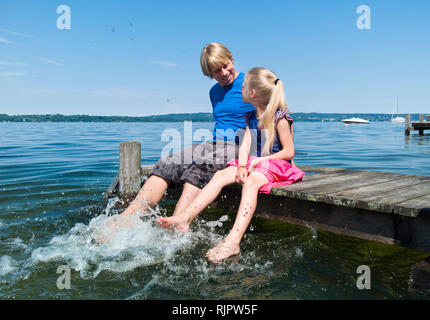 Padre e figlia piedi di raffreddamento in acqua, il lago di Starnberg, Baviera, Germania Foto Stock