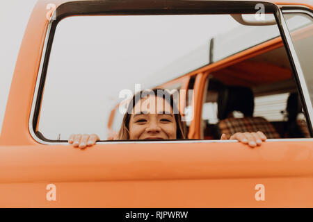 Giovane donna spiata attraverso il veicolo per attività ricreative finestra in spiaggia, ritratto, Jalama, CALIFORNIA, STATI UNITI D'AMERICA Foto Stock