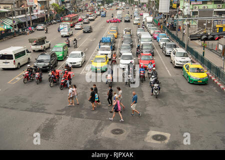 Una strada trafficata giunzione nella città di Bangkok in Thailandia da una vista in elevazione che mostra pedoni che attraversano un incrocio a semafori. Foto Stock