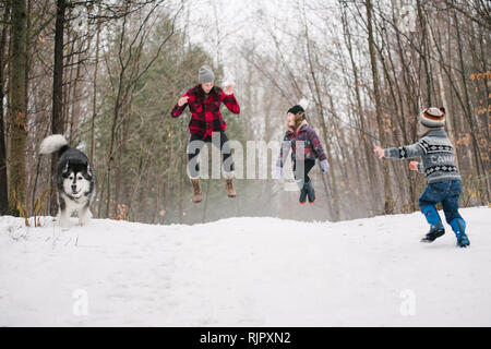 Famiglia con cane giocando nel paesaggio di neve Foto Stock