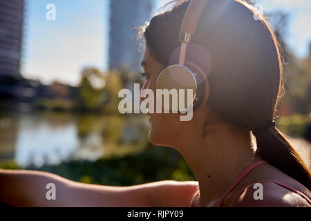 Donna l'ascolto di musica con le cuffie nel parco della città Foto Stock