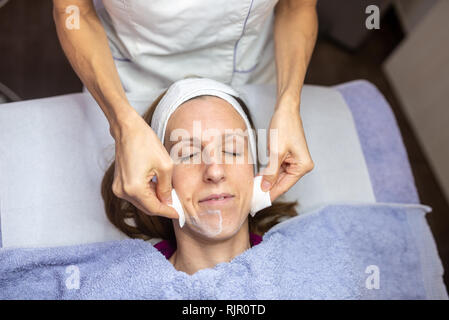 Vista superiore della giovane donna che giace disteso su un lettino da massaggio mentre ottenere un lavaggio massaggio del viso e per la cura della pelle. Foto Stock