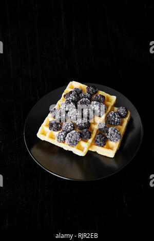 Cialde belghe con congelati more su uno sfondo nero. Foto Stock
