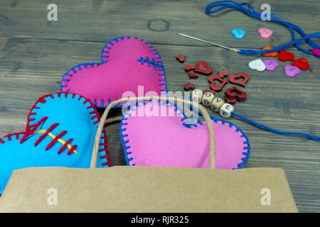 Sacchetto di carta pieno di cuore a mano souvenir e lettere di amore su legno rustico sfondo. Amore, relazione, il giorno di San Valentino, cuore spezzato concept Foto Stock