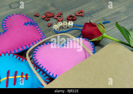 Sacchetto di carta pieno di cuore a mano souvenir, rose e lettere di amore su legno rustico sfondo. Amore, relazione, il giorno di San Valentino, cuore spezzato concep Foto Stock