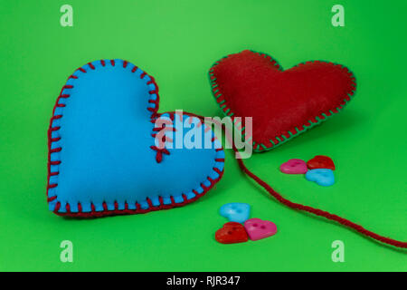 A forma di cuore cucito a mano cuori tessili realizzati in tessuto di colore rosa e cucita con fili blu sul verde Chroma Key per sfondo romantico San Valentino o con Foto Stock