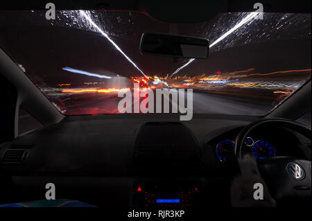 Misty e condizioni di nebbia di notte con la valanga di neve in inverno britannico su una autostrada e strade con traffico incombente Foto Stock