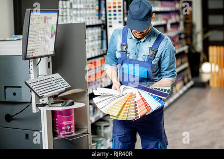 Ritratto di un bel operaio con campioni di colore nelle vicinanze dell'apparecchiatura per la colorazione nella costruzione shop Foto Stock