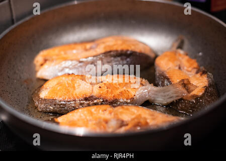 Salmone fritto in padella. La cottura di filetti di salmone. Foto Stock