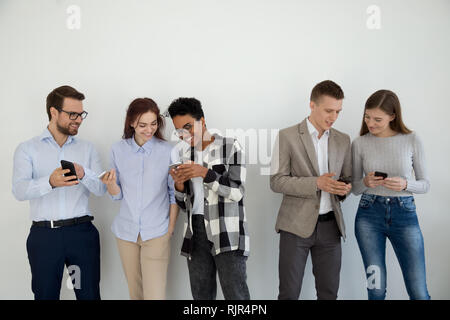 Felice multi etnico amici o imprenditori usano telefoni parlando Foto Stock