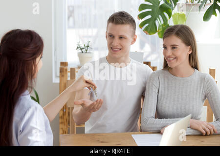 Coppia felice i proprietari ottengono le chiavi di casa nuova da agente immobiliare Foto Stock