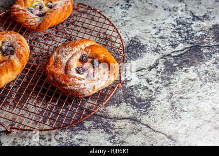 Vista superiore del golden formaggio danese pasties con more e zucchero in polvere Foto Stock