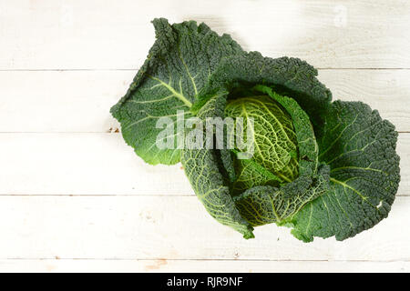 Green verza, una sana verdura invernale, tutta la testa su rustiche in legno bianco con copia spazio, elevato angolo vista da sopra, messa a fuoco selezionata Foto Stock