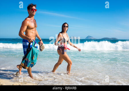 RIO DE JANEIRO - febbraio, 2017: una giovane coppia a piedi con uno zaino in fondali bassi della spiaggia di Ipanema, che ha visto un drammatico aumento dei furti. Foto Stock