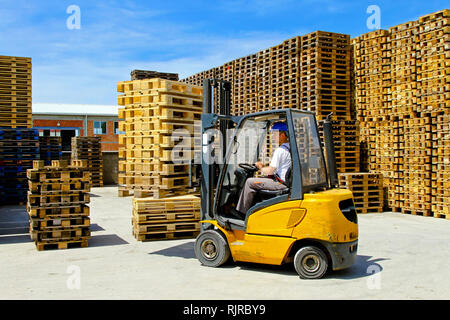 L'operatore del carrello di movimentazione pallet di legno in magazzino Foto Stock