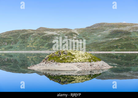 La riflessione di isola nel Lago di Tyin circondato da montagne Jutunheimen, Norvegia, Europa Foto Stock