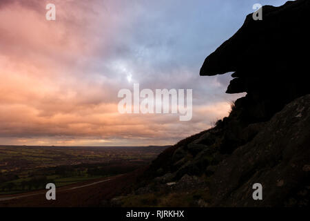 Sunset over il Pancake di pietra che, quando si stagliano, assomiglia a una faccia, Ilkley Moor e Burley Moor guardando attraverso Wharfedale Foto Stock