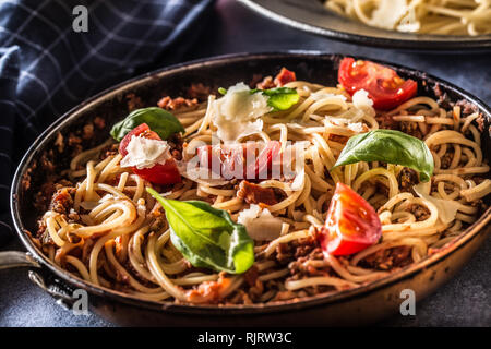 La pasta italiana spaghetti alla bolognese vecchia in padella con pomodori formaggio parmigiano e basilico Foto Stock