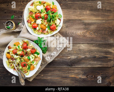 Fettuccine con pomodori al forno, pancetta e formaggio mozzarella su legno rustico sfondo. Vista dall'alto. Foto Stock