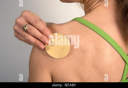 Donna sticking Nicotine patch sul suo braccio Foto Stock