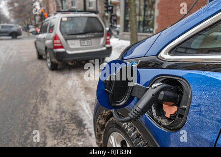Montreal, Canada - 7 February 2019: auto elettrica collegata e la ricarica nella stagione invernale su Gilford Street. Foto Stock