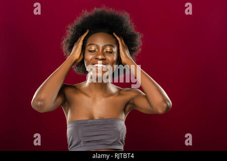 Felice donna positiva di toccare i suoi capelli ricci Foto Stock