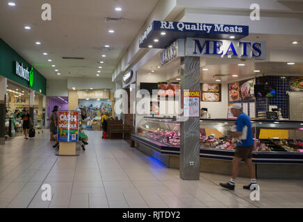 Interno del moderno centro commerciale con persone che passeggiano attraverso mall passato macelleria e supermercato Foto Stock