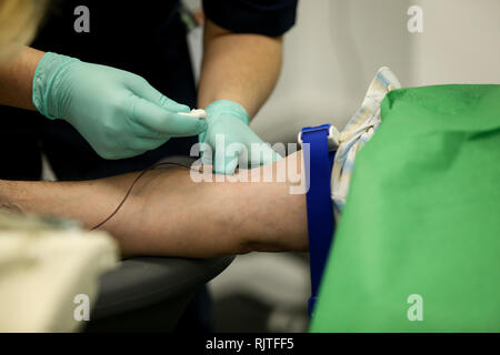 Dettagli con le mani di un medico, gomma da indossare i guanti chirurgici, prelievo di sangue dalla vena di un paziente con un catetere Foto Stock