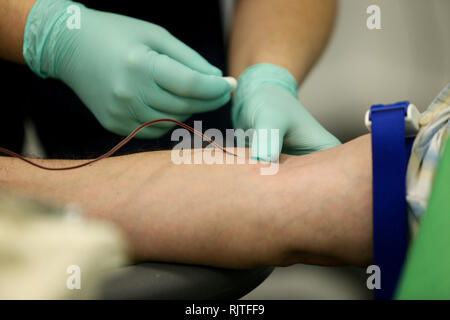 Dettagli con le mani di un medico, gomma da indossare i guanti chirurgici, prelievo di sangue dalla vena di un paziente con un catetere Foto Stock