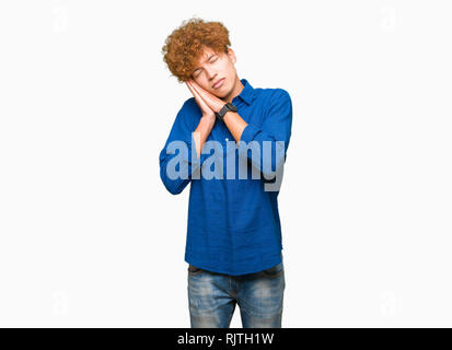 Bel giovane uomo elegante con capelli afro dormire stanchi di sognare e in posa con le mani insieme mentre sorridente con gli occhi chiusi. Foto Stock