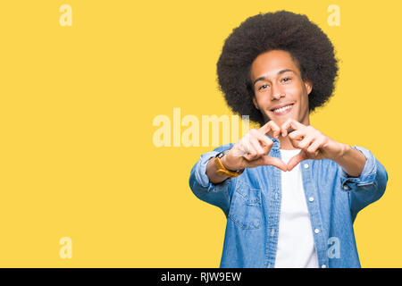 Giovane americano africano uomo con capelli afro sorridente in amore che mostra il simbolo del cuore e la forma con le mani. Concetto romantico. Foto Stock