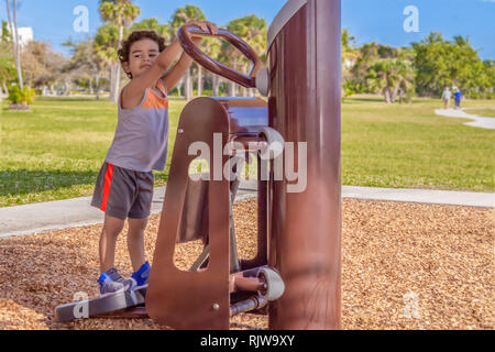 Il giovane ragazzo arriva all'aperto sulla Stairmaster guardando oltre l'altro lato per sua madre. Il ragazzino mantiene un occhio vigile sulla mamma. Foto Stock